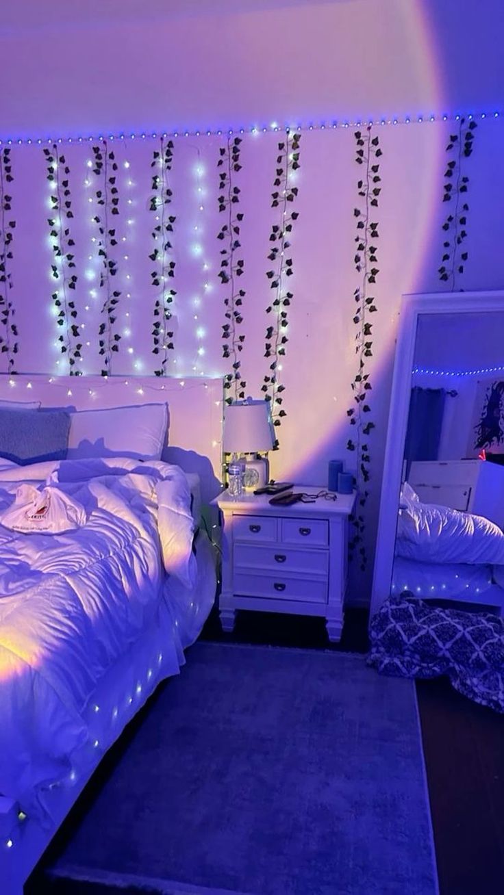 a bedroom decorated in purple and white with string lights on the headboard, dressers and bed