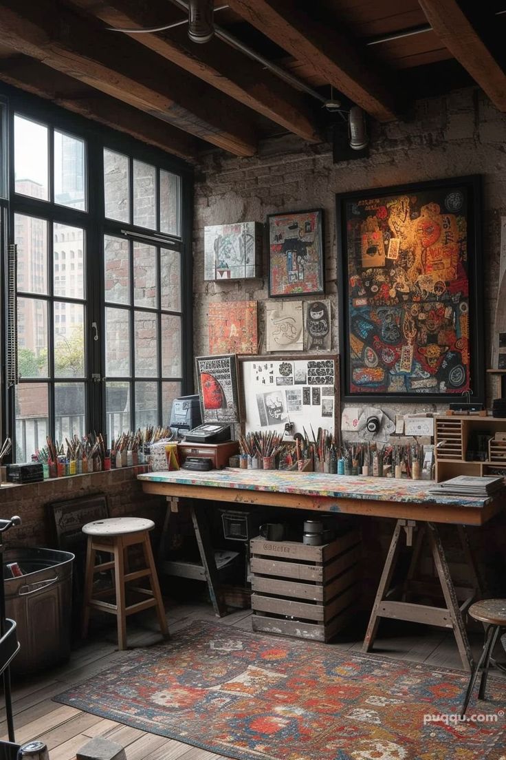 an art studio with large windows and lots of artwork on the wall, including paintings