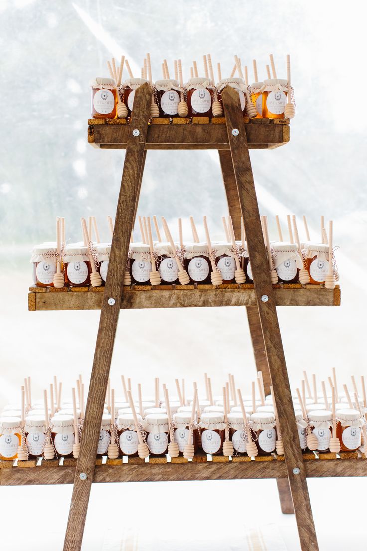 there are many jars on the wooden stand with toothpicks in them and one is filled with honey