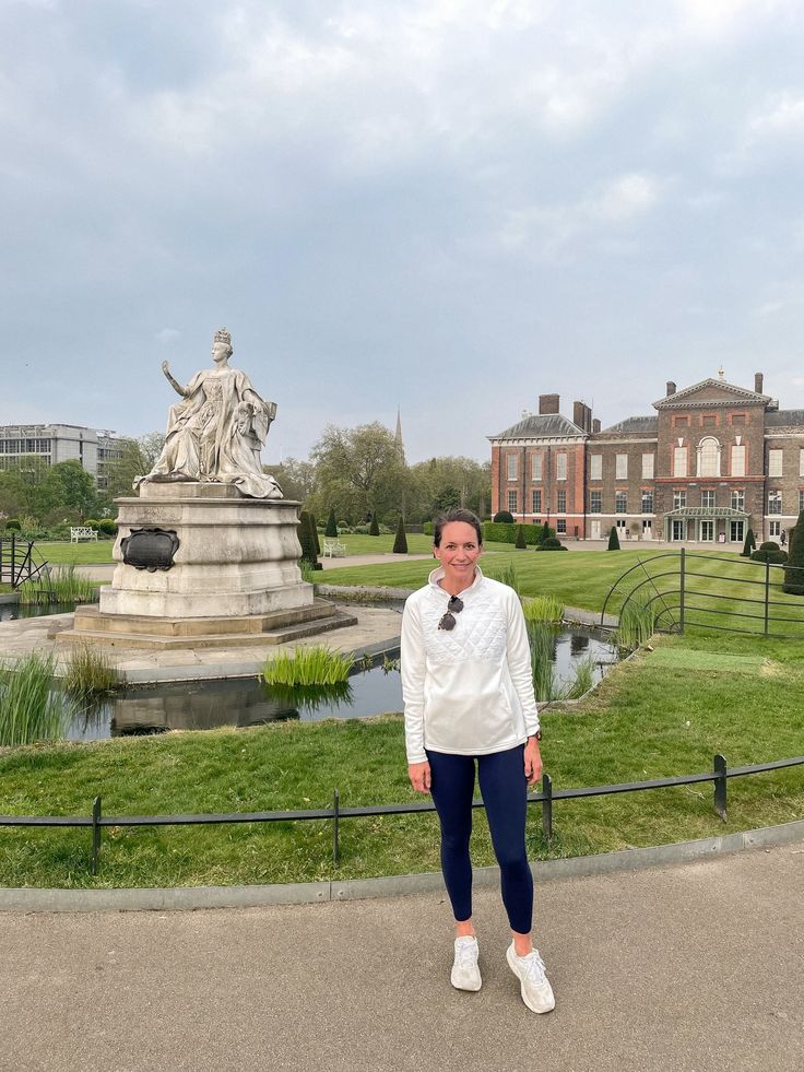 a woman standing in front of a large building with a statue on the other side