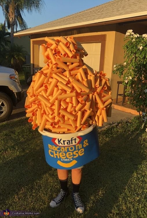 a person standing in the grass holding a bucket full of french fries