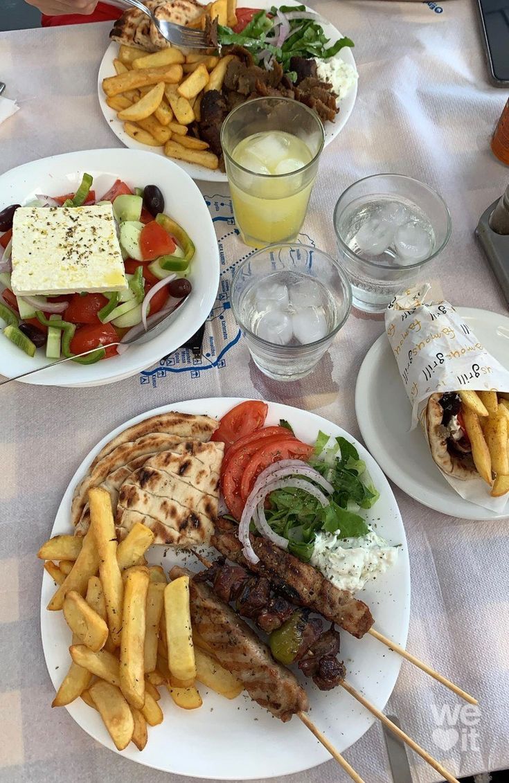 a table topped with plates of food next to glasses of juice and water on top of a white table cloth