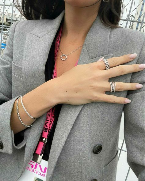 a woman with two rings on her left hand wearing a gray blazer and pink shirt