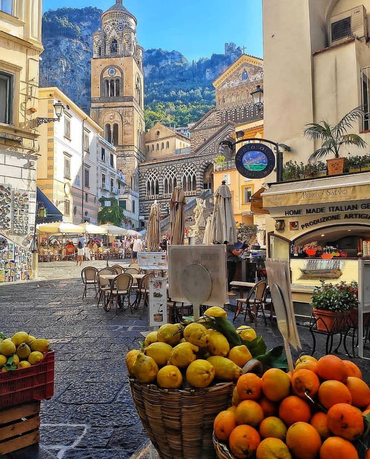 there are many fruits and vegetables on display in this street side market area, including oranges