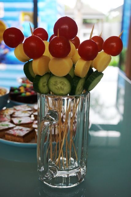 a vase filled with cucumbers and cherries on top of a blue table