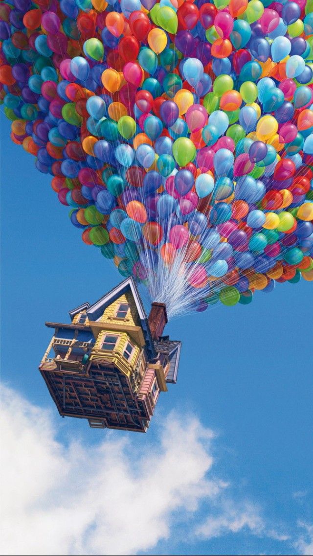 a large group of balloons are being released into the sky by a house on stilts