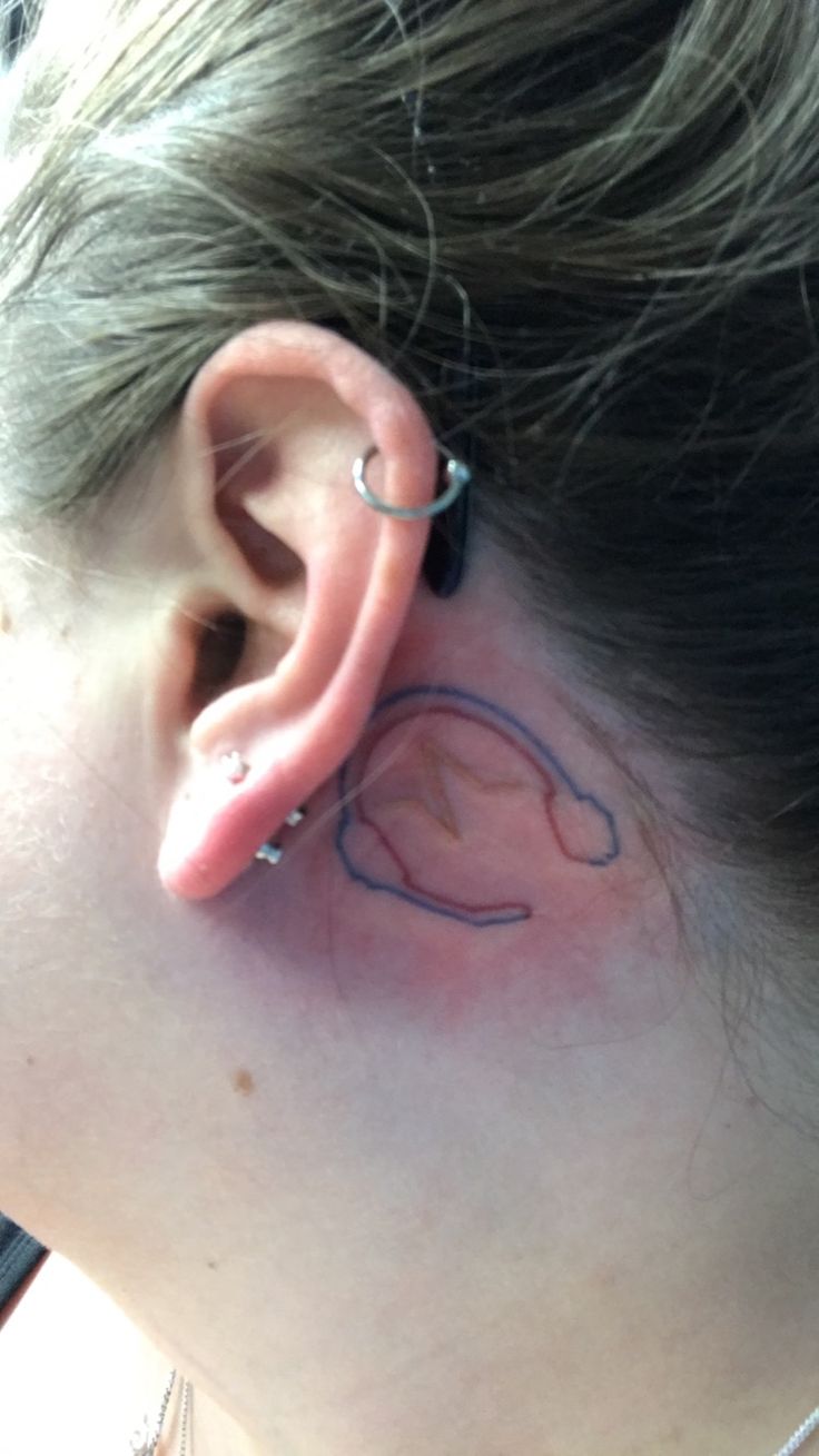 a woman's ear has a small tattoo on it