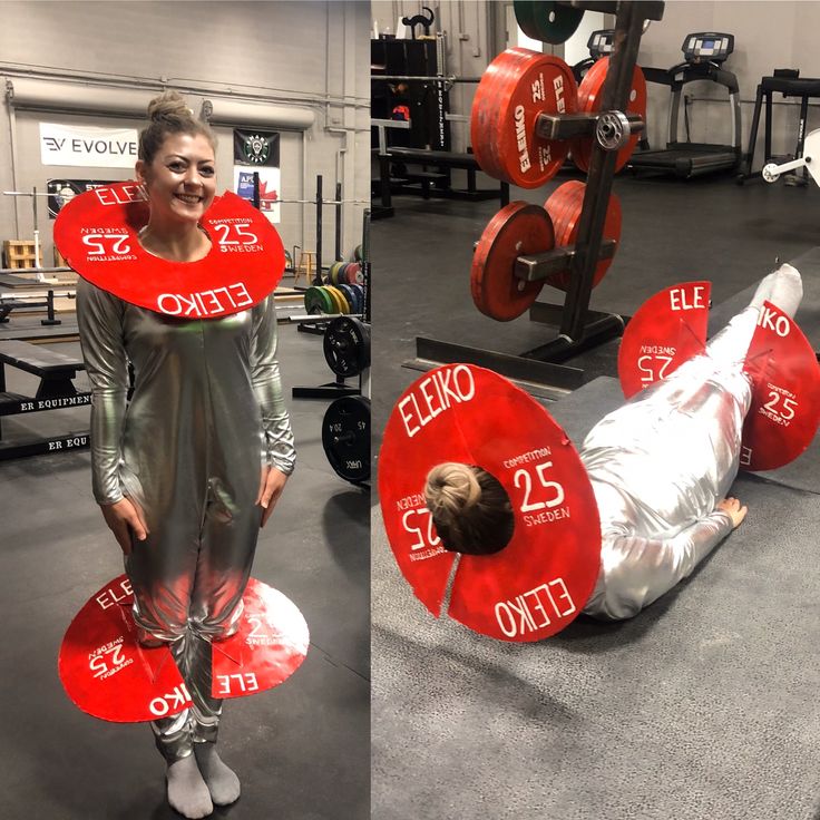 a woman standing next to a man laying on top of a red object in a gym