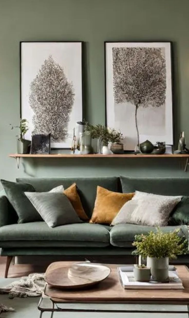 a living room with green walls and two pictures on the wall above the couches