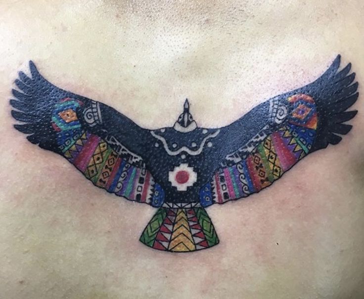 a tattoo on the back of a man's chest with an eagle and flowers