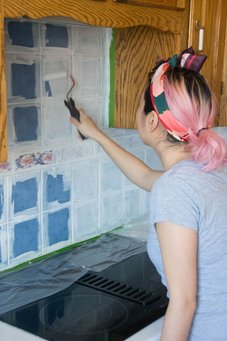 a woman with pink hair painting a kitchen wall