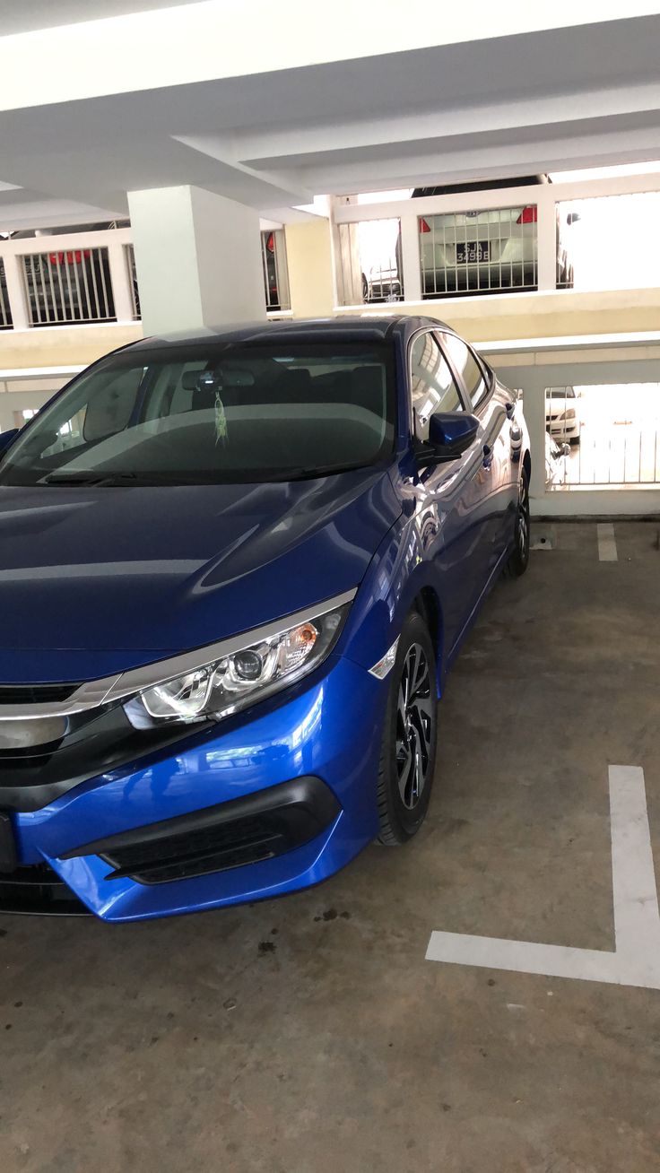 a blue car is parked in a parking lot next to another car and some windows