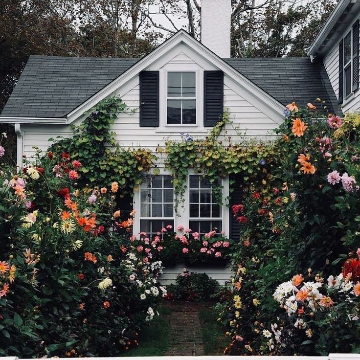 a white house with lots of flowers around it