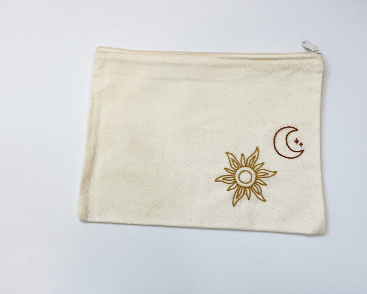 a white pouch with embroidered sun and moon on it