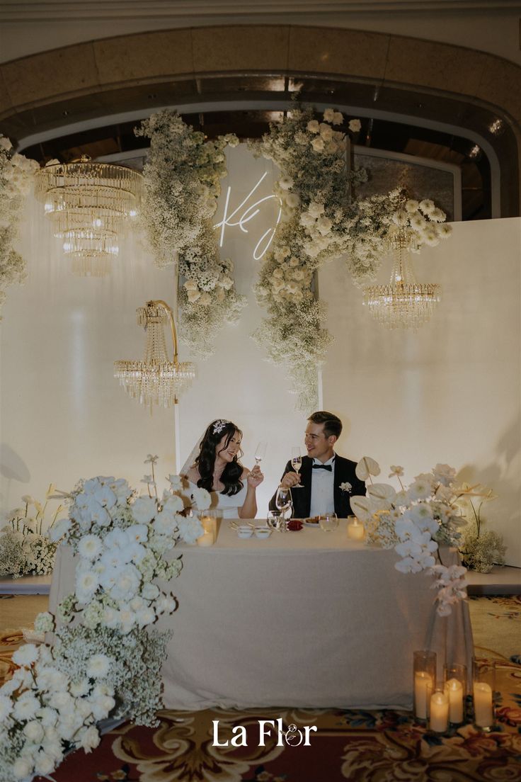 two people sitting at a table with flowers and candles