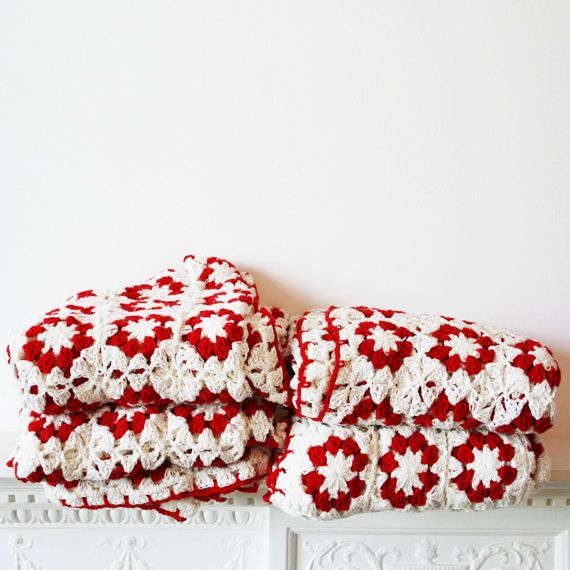 four red and white crocheted blankets stacked on top of each other in front of a wall