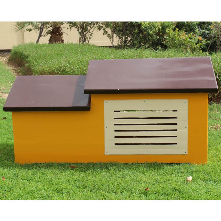 a yellow and brown dog house sitting in the grass