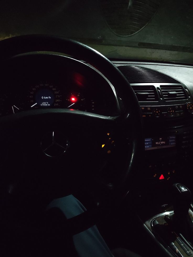 the interior of a car with dashboard lights and steering wheel controls lit up at night