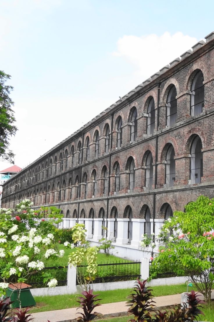 an old brick building with many windows and plants in front of it on a sunny day