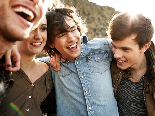 four young people are smiling and posing for the camera with their arms around each other