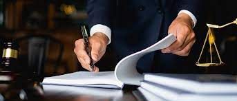 a man in a suit writing on paper next to a judge's scale