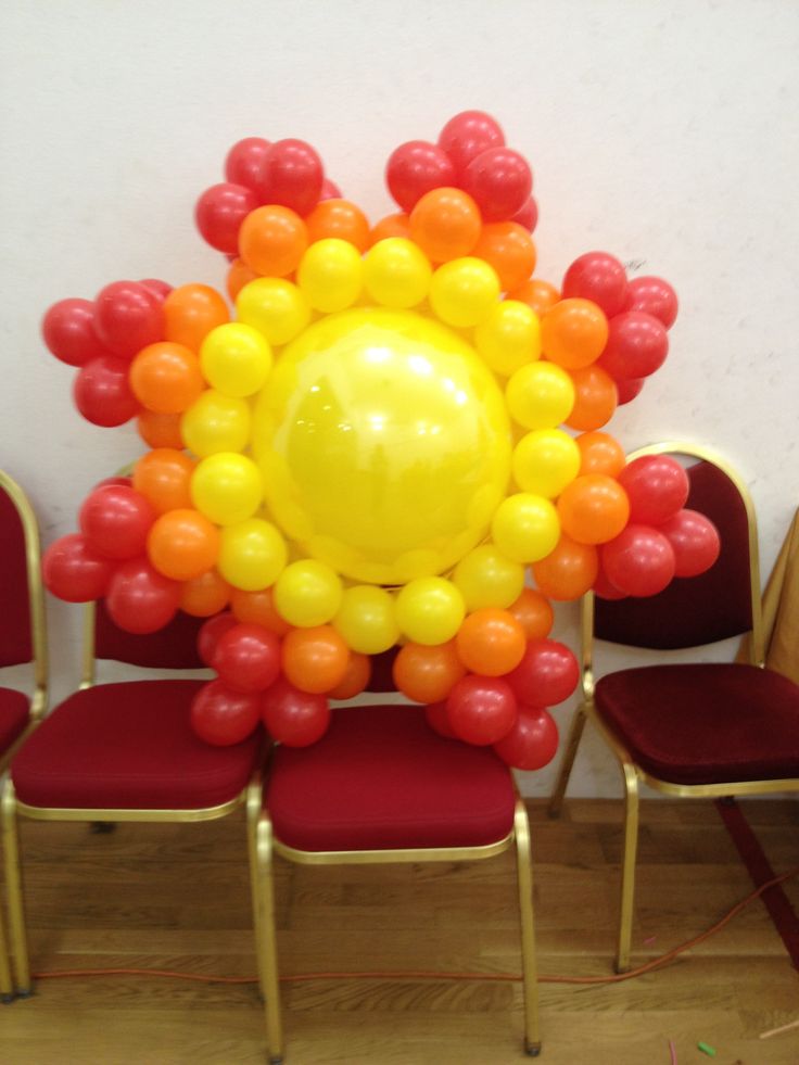 a bunch of red chairs with balloons on them in front of a yellow ballon sun