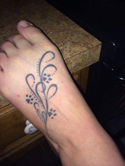 a person's foot with a tattoo design on the left side of their leg