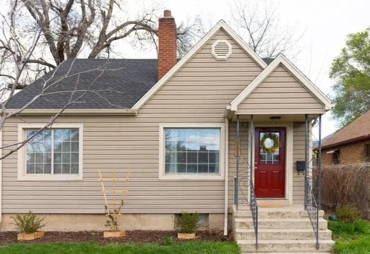 a small house with a red door and steps leading to the front door is shown