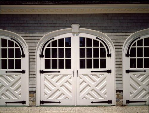 three white double doors with arched windows on the side of a building