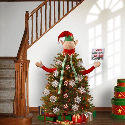 a christmas tree with an elf holding a sign