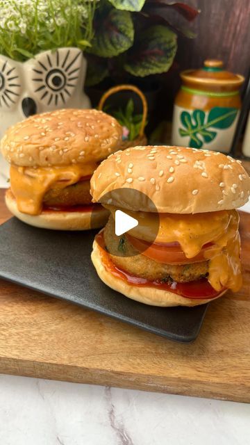 two hamburgers sitting on top of a cutting board