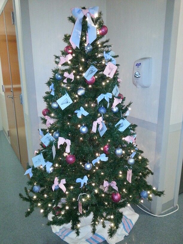 a decorated christmas tree in an office cubicle with blue and pink bows on it