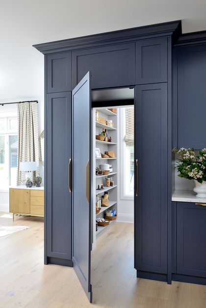 an open closet in the middle of a room with blue cabinets and shelves on each side