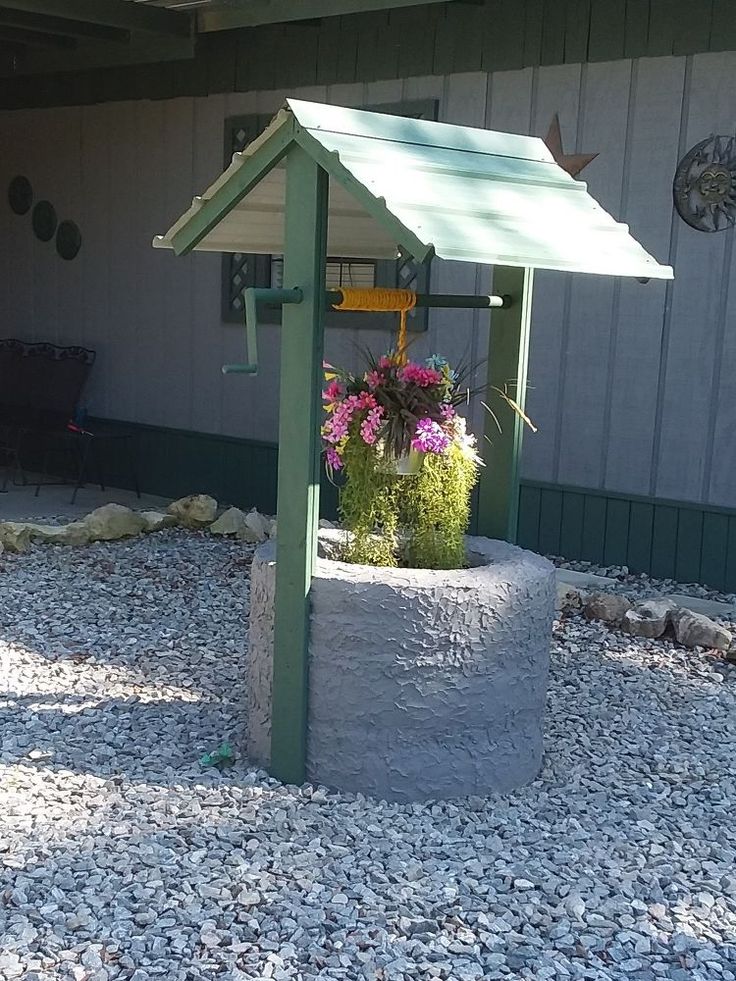 a green and white gazebo sitting on top of a gravel covered ground next to a building