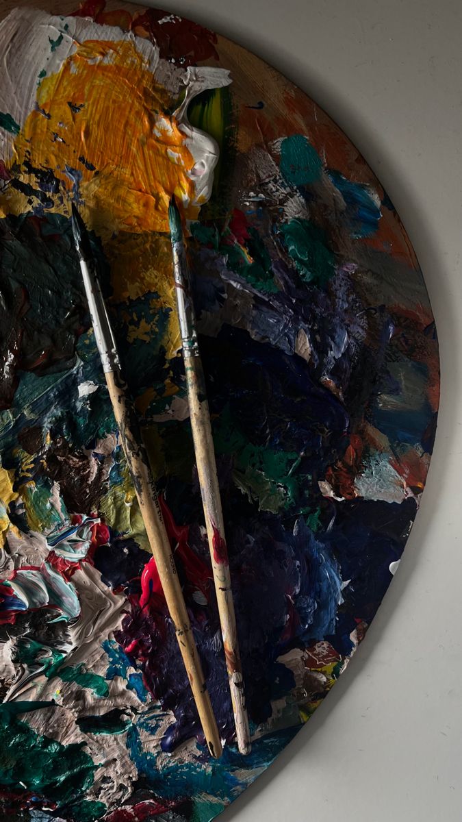 two paintbrushes sitting on top of an art palette