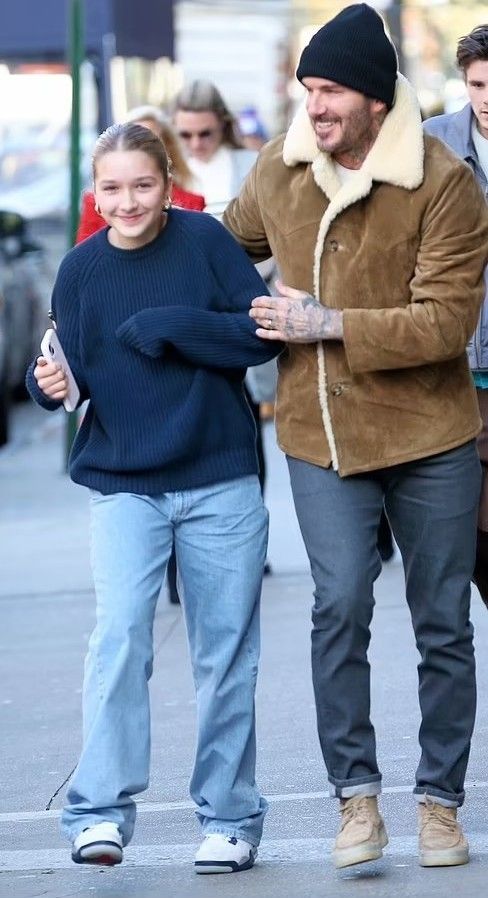 a man and woman walking down the street with one holding his arm around the other