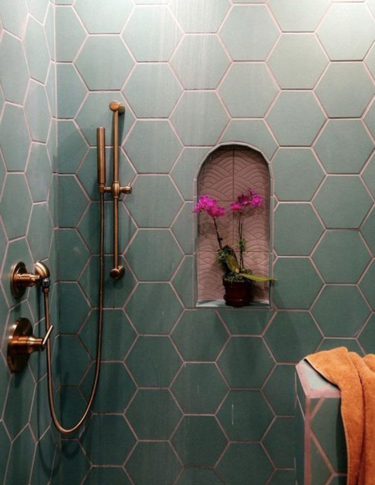 a green tiled bathroom with pink flowers in the window