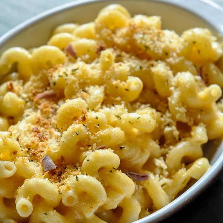 a white bowl filled with macaroni and cheese covered in seasoning on top of a table