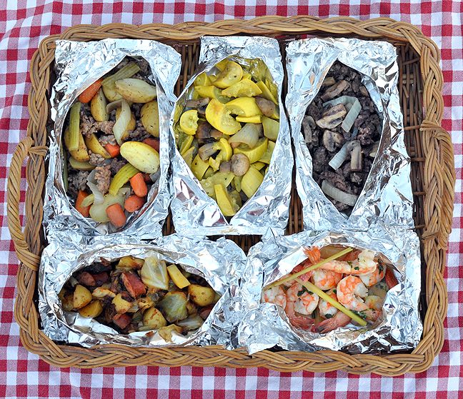 four trays filled with food sitting on top of a checkered tablecloth covered table