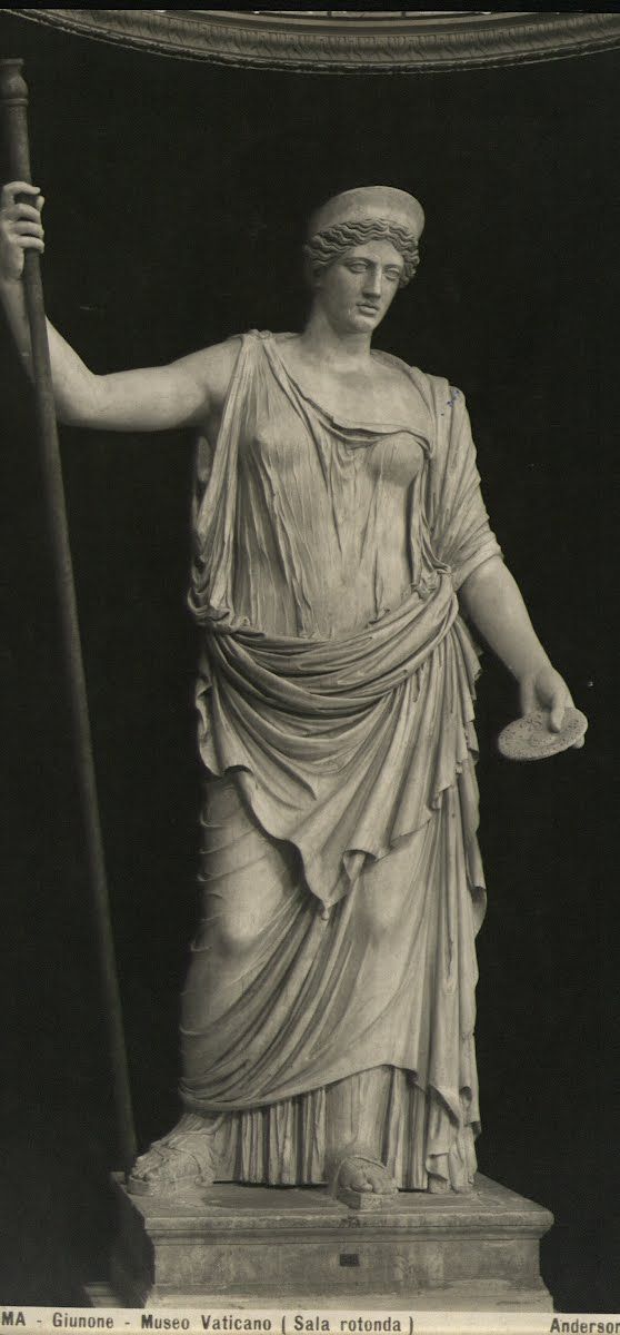 an old black and white photo of a statue with a staff in it's hand