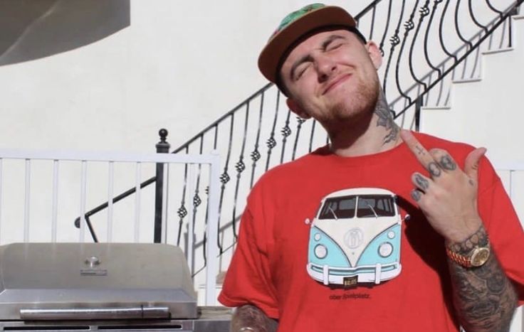 a man in a red shirt and hat standing next to a bbq with a vw bus on it