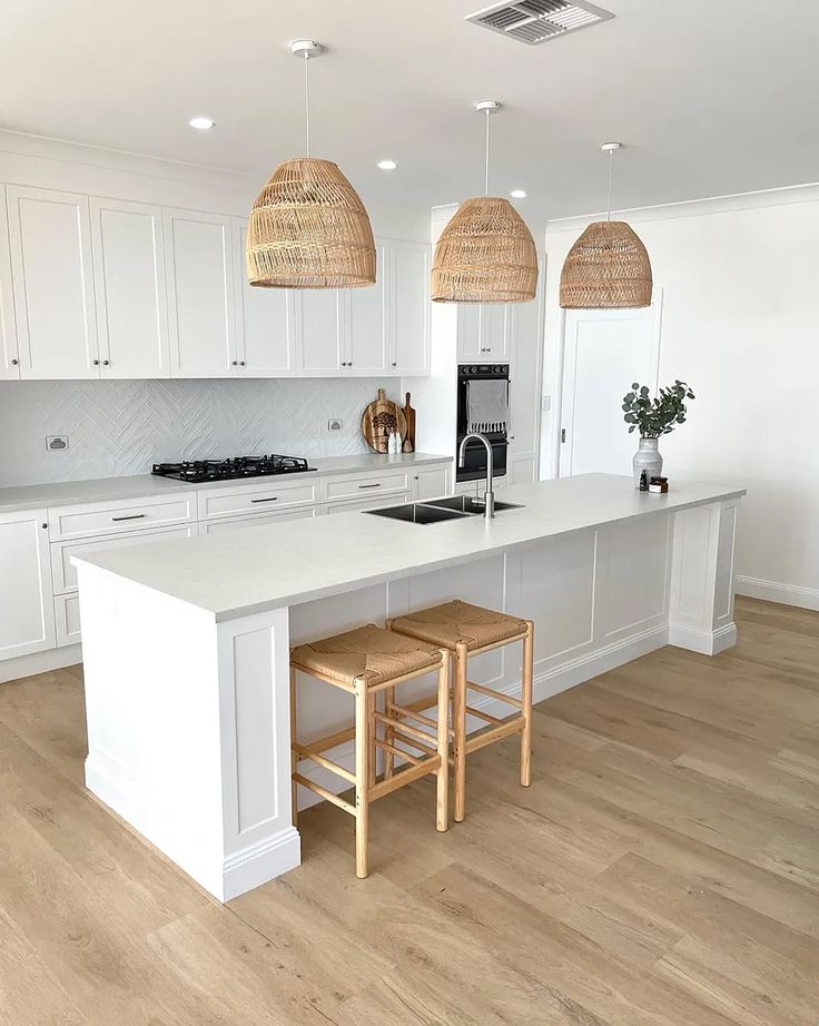 a large white kitchen with two stools in front of the counter and an island