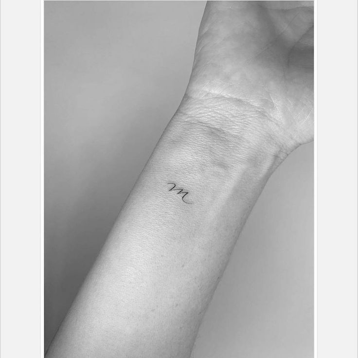 a person's arm with a small tattoo on the left side of their wrist