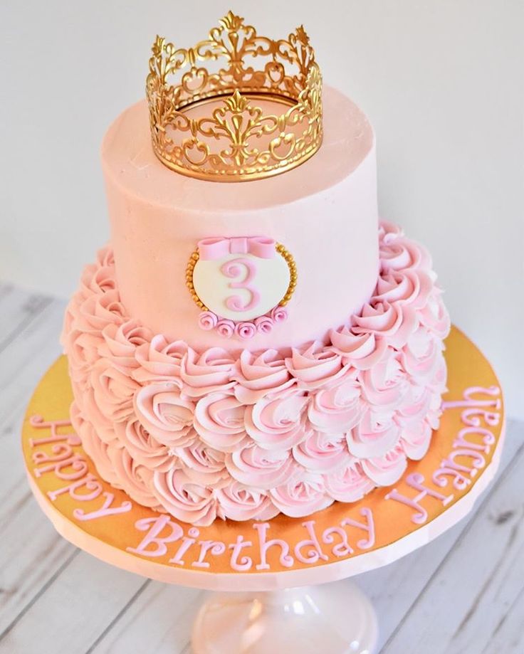 a pink and gold birthday cake with a crown on top