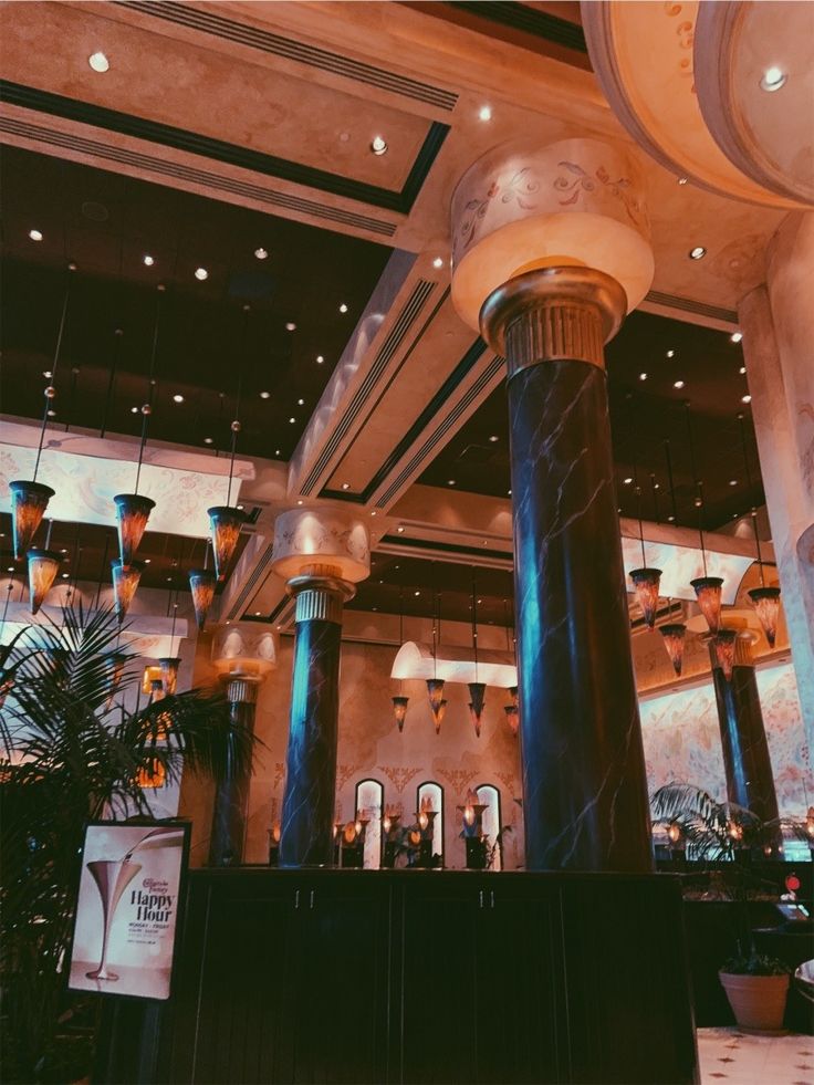 the interior of a restaurant with columns and chandeliers