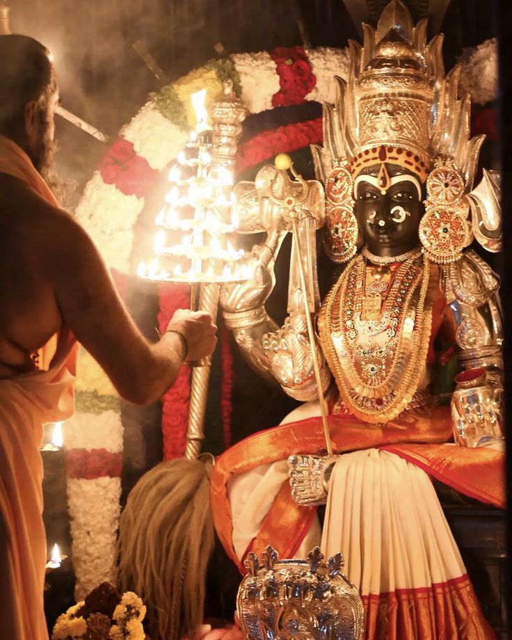 a man lighting candles on the face of a statue in front of a woman sitting down