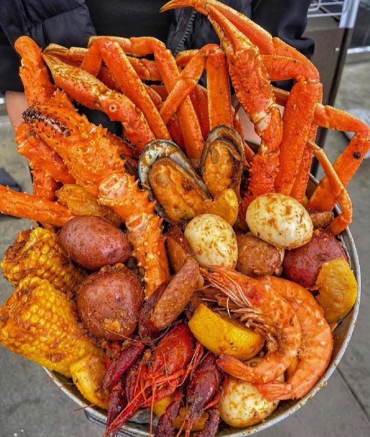 a bucket filled with lots of different types of food on top of a street side