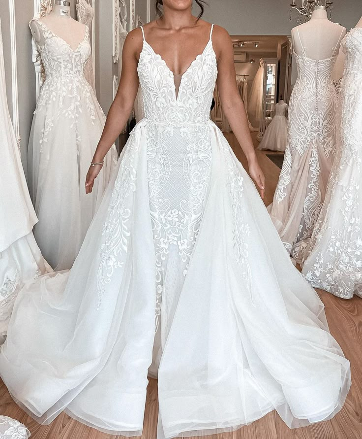 a woman in a white wedding dress standing next to dresses on mannequins