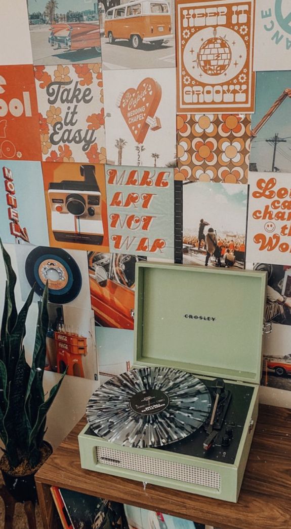 a record player sitting on top of a wooden table next to a plant and pictures