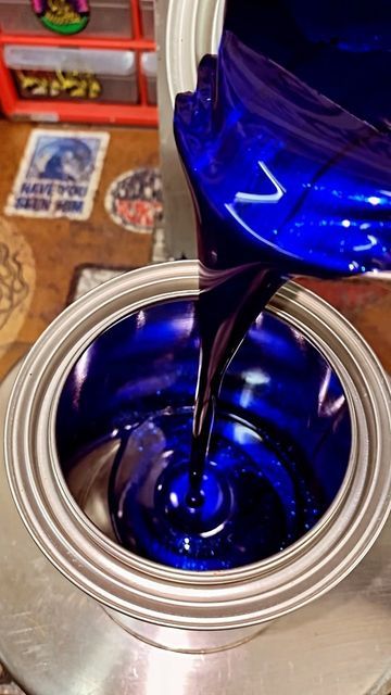 the blue liquid is being poured into the metal bowl on top of the silver object